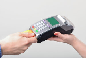 Hände mit einer Bankkarte und einem mobilen Kartenterminal