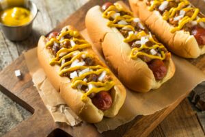 Coney Dogs: Hot Dogs mit Chili, Zwiebeln und Senf auf Holzbrett