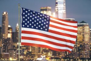 US-Flagge vor einer Skyline als Symbol für Reisen in die USA.