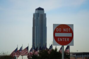 Do-not-enter-Schild vor US-Flaggen und Grenzgebäude als Symbol für eine abgelehnte Einreise.