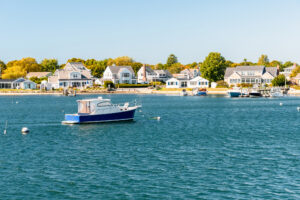 Motorboot legt an der Küste von Cape Cod an einem sonnigen Herbsttag an, umgeben von ruhigem Wasser und herbstlich gefärbten Bäumen.