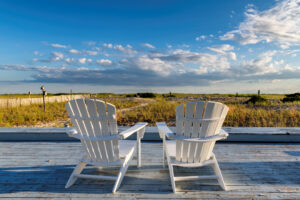 Weitläufiger Sandstrand auf Cape Cod mit sanften Wellen, grasbewachsenen Dünen und blauem Himmel.