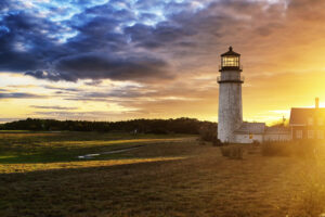 Highland Lighthouse bei Sonnenuntergang, umgeben von malerischen Sanddünen und leuchtendem Himmel.