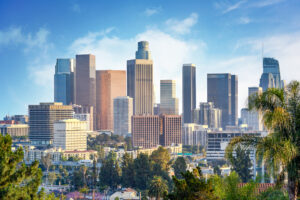 Skyline von Downtown Los Angeles mit Palmen im Vordergrund unter blauem Himmel