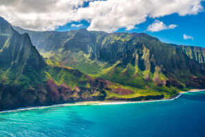 Steile grüne Küste von Kauaʻi mit türkisblauem Meer