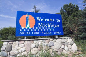 Blaues Willkommensschild in Michigan mit Leuchtturm-Motiv und dem Schriftzug Welcome to Michigan – Great Lakes, Great Times