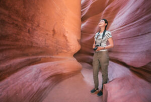 Besucherin mit Kamera zwischen den roten Sandsteinwänden im Antelope Canyon