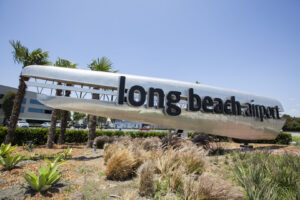 Schriftzug des Long Beach Airport vor Palmen und blauem Himmel