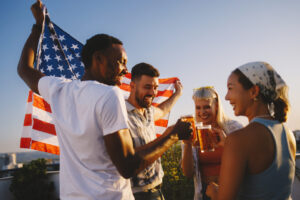 Menschen stoßen bei einer Feier im Freien vor einer US-Flagge an