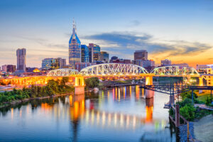 Skyline von Nashville am Cumberland River mit beleuchteter Brücke bei Sonnenuntergang