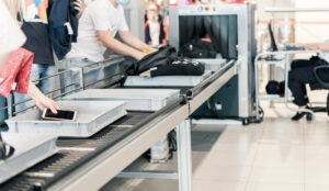Sicherheitskontrolle am Flughafen mit Handgepäck und Smartphone auf dem Kontrollband