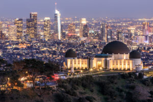 Beleuchtetes Griffith Observatory mit der Skyline von Downtown Los Angeles im Hintergrund