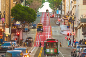 Drei Cable Cars auf einer steilen Straße im Zentrum von San Francisco.