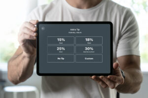 Mann hält ein Tablet mit einer Trinkgeld-Auswahl im Restaurant