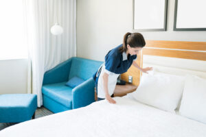 Housekeeping-Mitarbeiterin richtet die Kissen auf einem Hotelbett