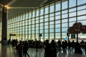 Reisende mit Gepäck vor der großen Fensterfront im Terminal A des Newark Airport